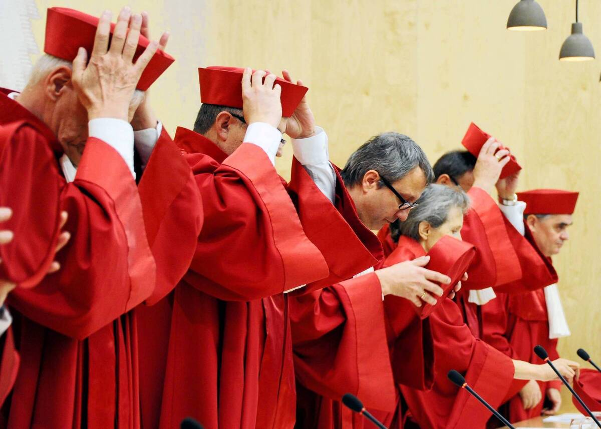 Judges of the Federal Constitutional Court adjust their caps before delivering a pronouncement about the euro crisis response in February in Karlsruhe, southern Germany. On Wednesday, eight judges are expected to deliver a landmark ruling on Germany’s participation in a European bailout fund.