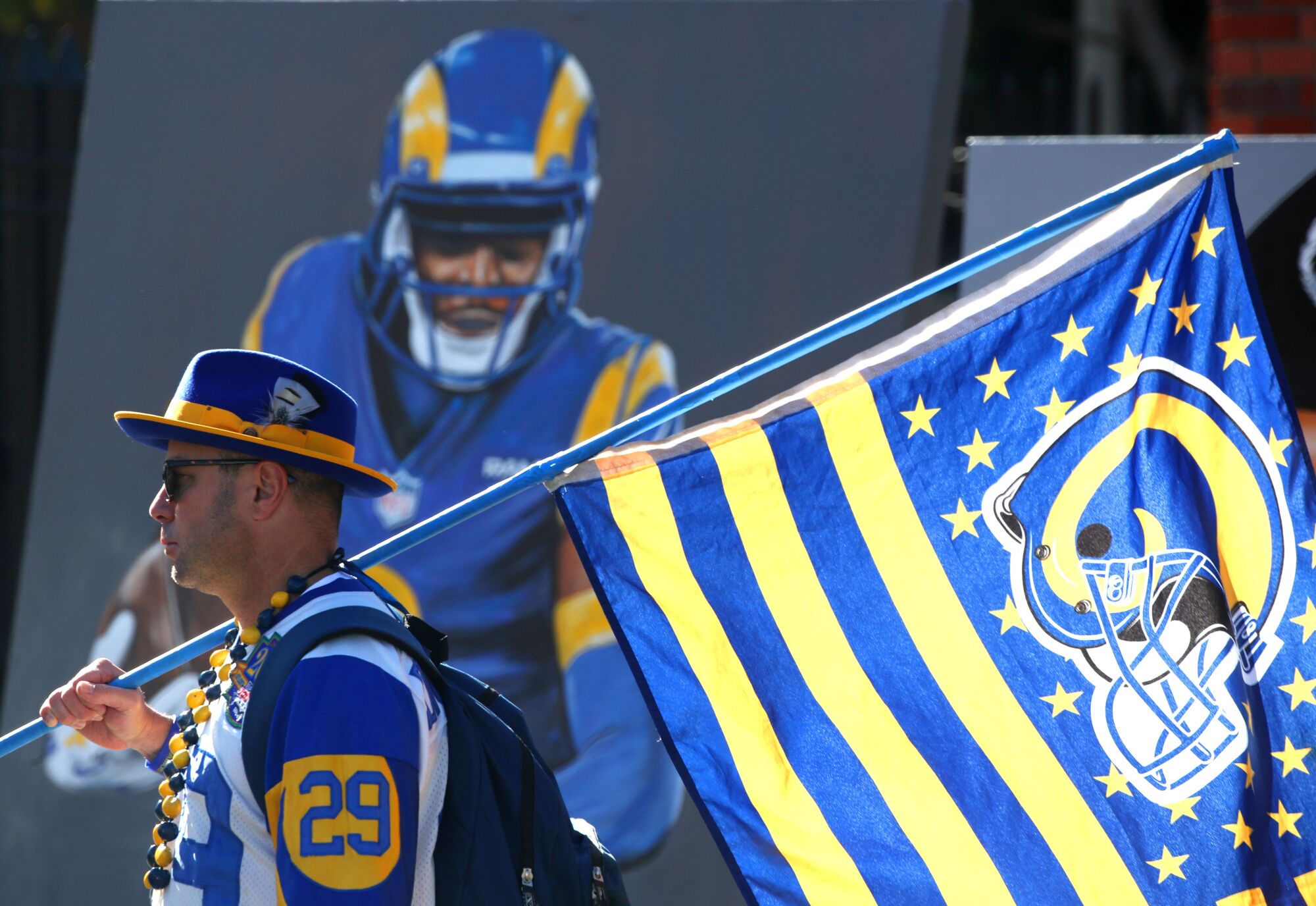 A fan carries a Rams flag past a mural.