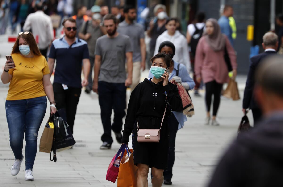 Shoppers, some wearing masks, walk along Oxford Street in London on Tuesday.
