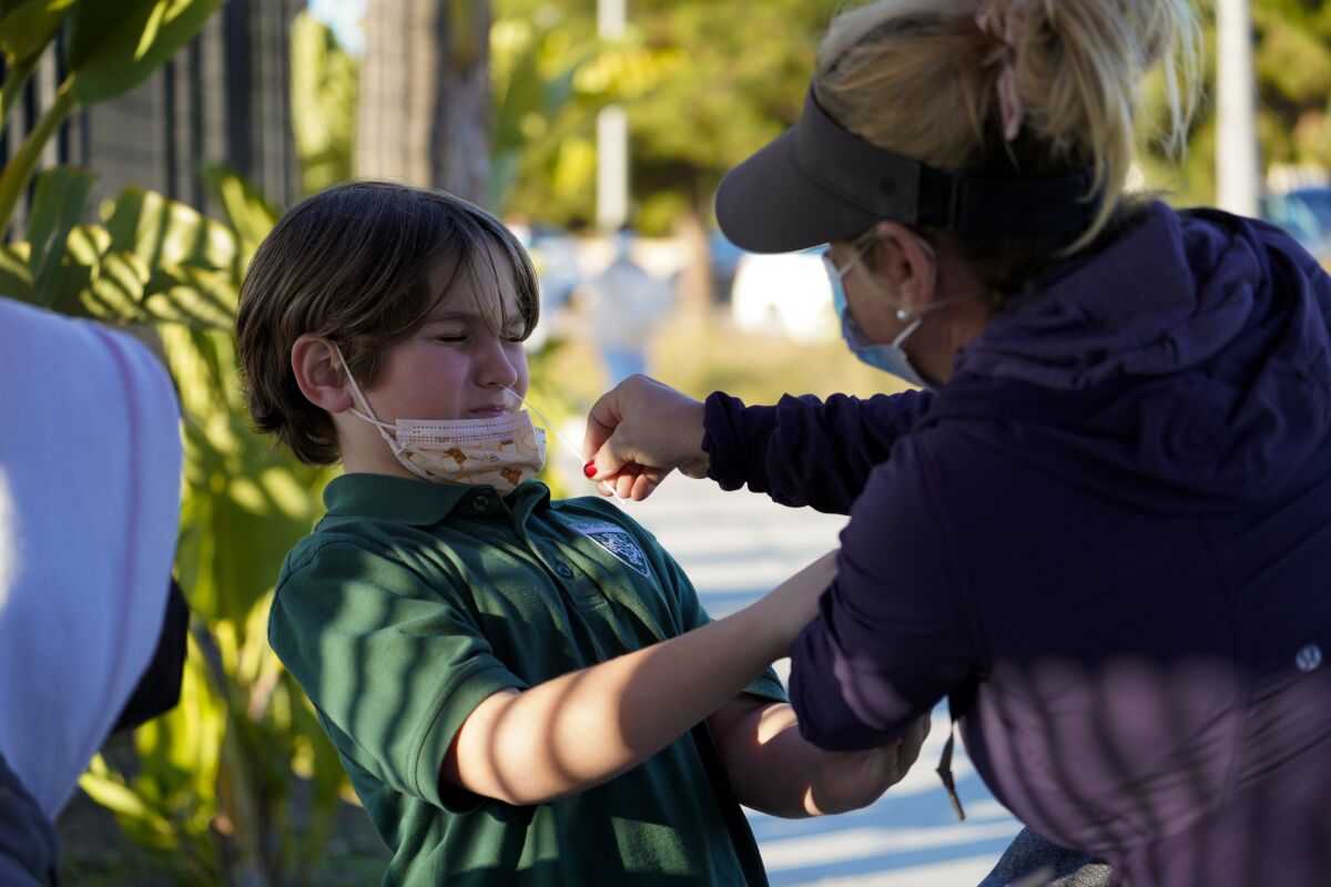 Stacey White performed a COVID test on her son, Timothy White, 10, at the COVID self-test site outside Carlsbad High.