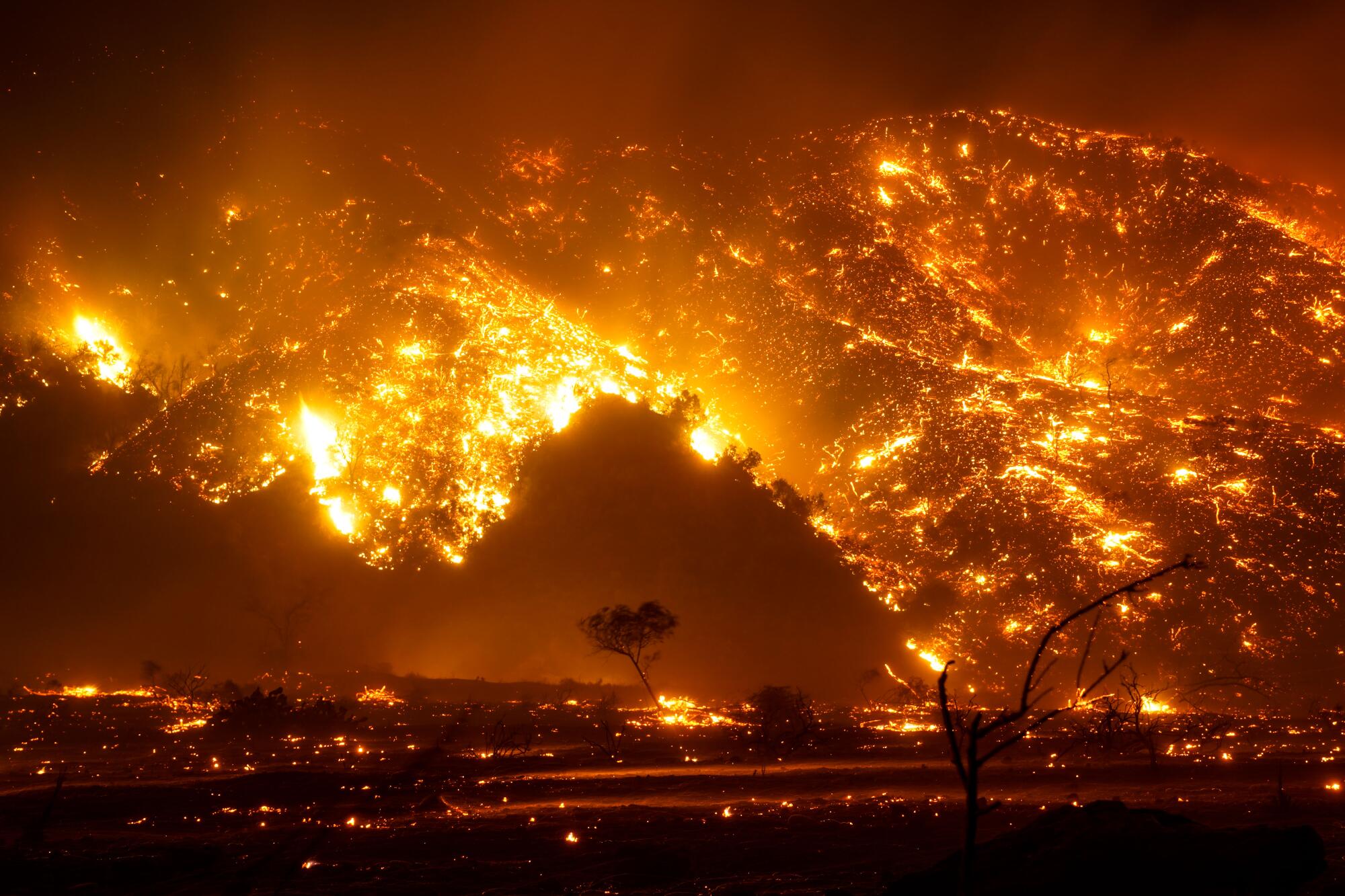 A hillside covered in flames and glowing orange embers at night