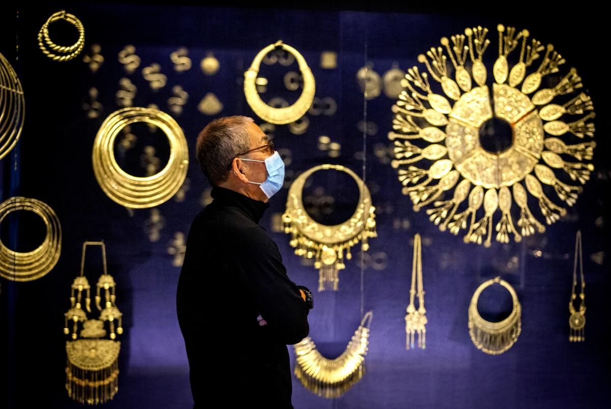  At Bowers Museum, a man stands in front of large ornaments made of silver.