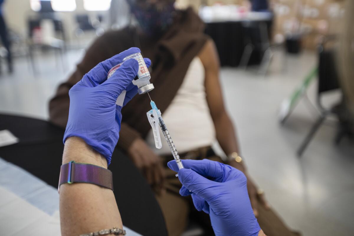 A syringe is loaded by hands wearing blue gloves