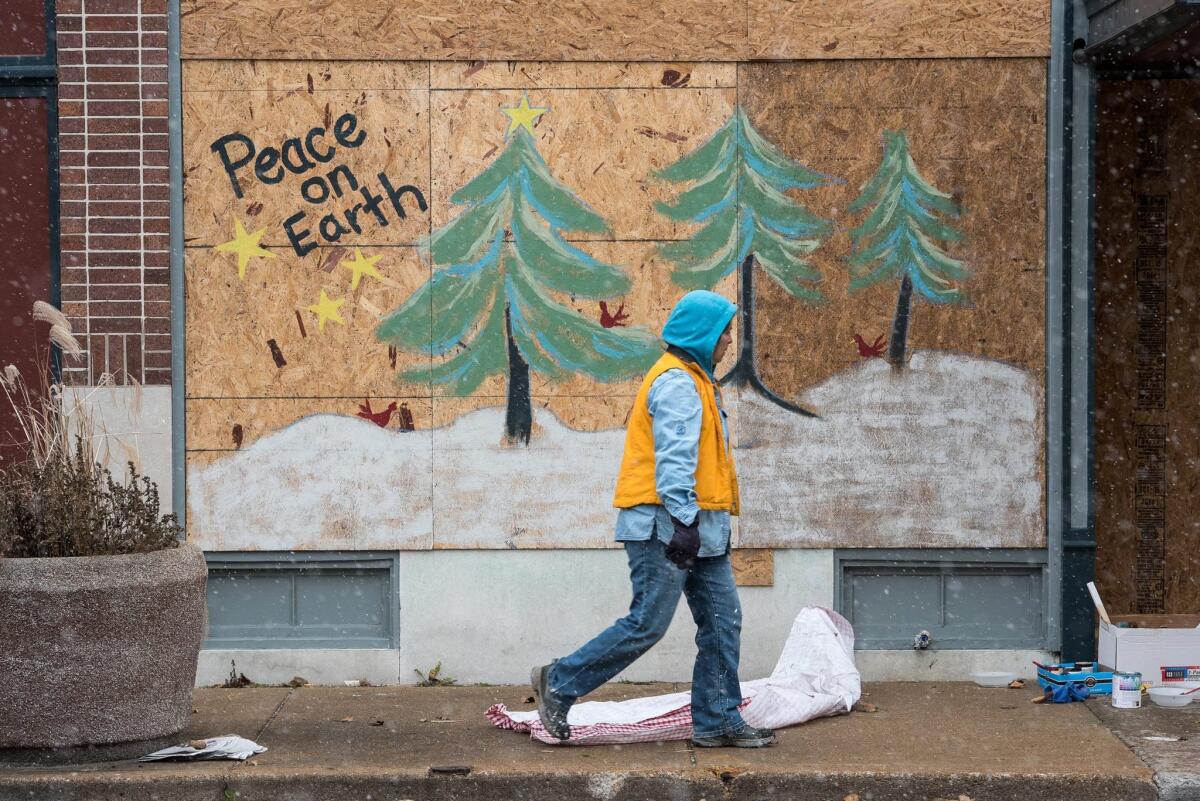 A woman passes a painting on a piece of plywood near Ferguson City Hall at the end of November. Missouri arts organizations want to preserve these as historical works of art.