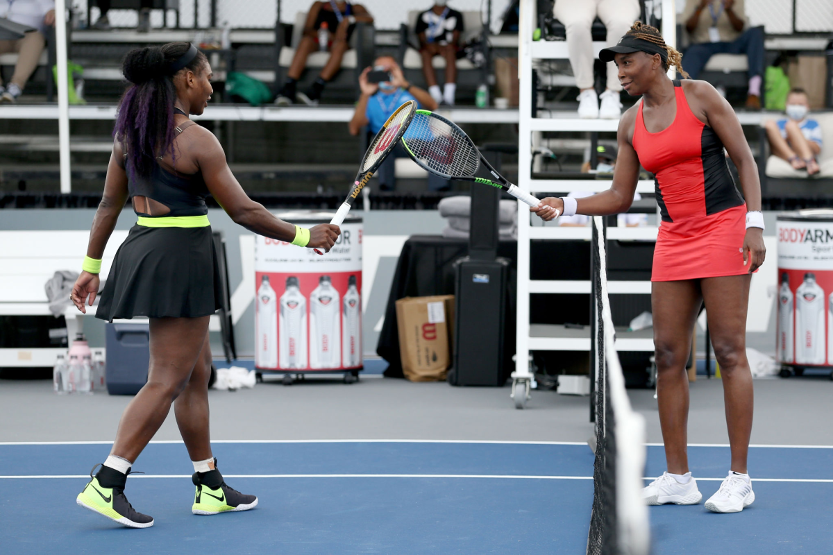 Serena, left, and Venus Williams touch rackets after their Top Seed match.