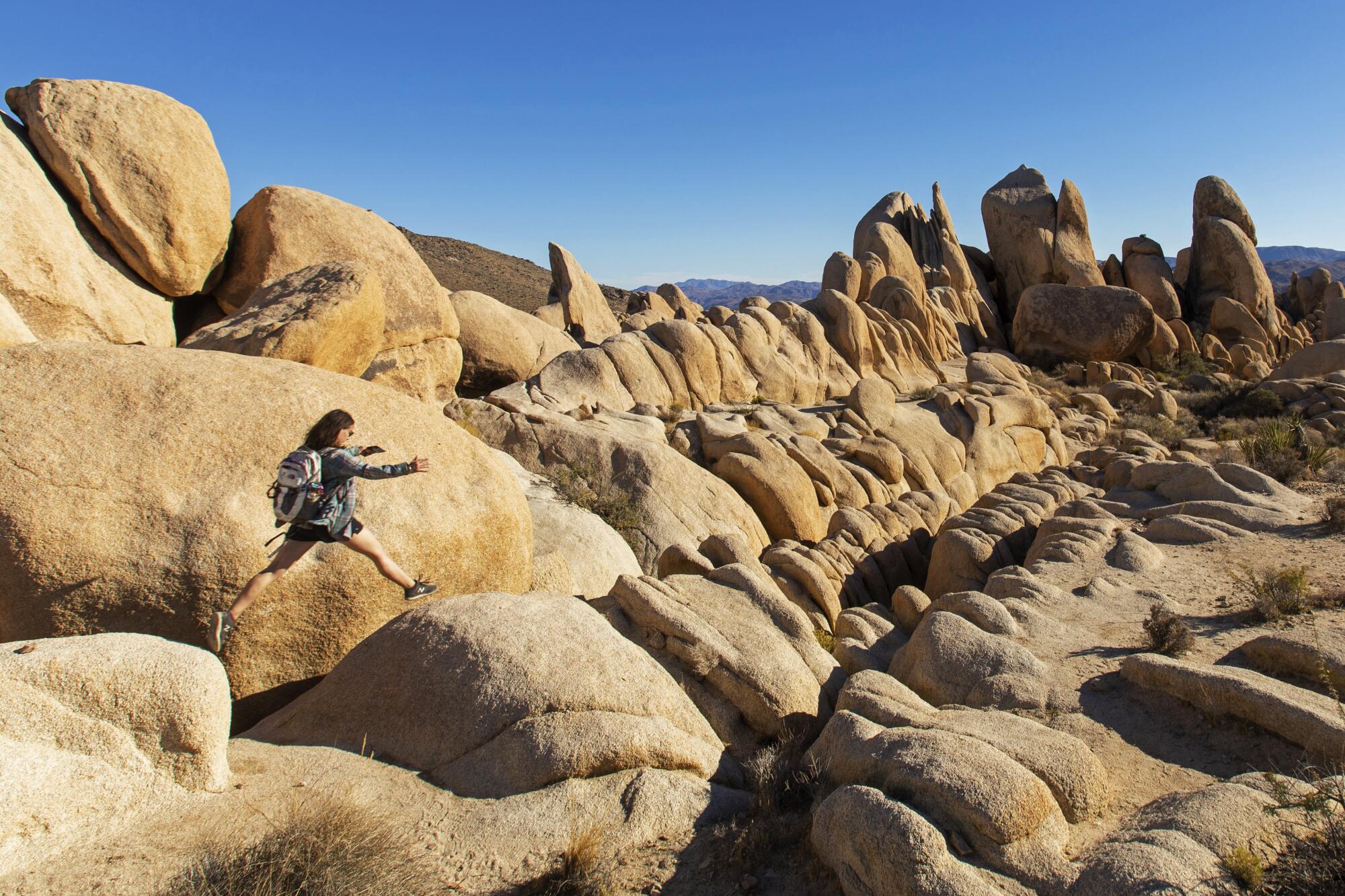 A person leaps forward on a giant rock formation.