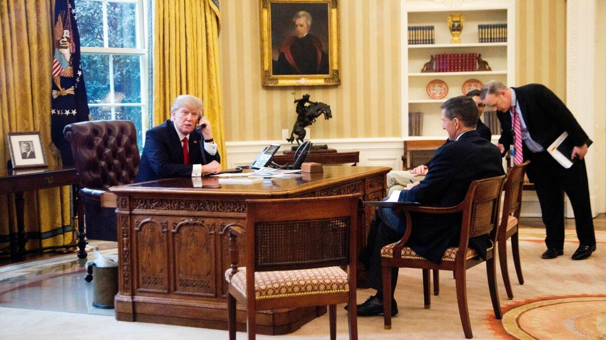 President Trump makes a call in the Oval Office on Jan. 29 with then-national security advisor Michael Flynn, seated right, on Jan. 29.