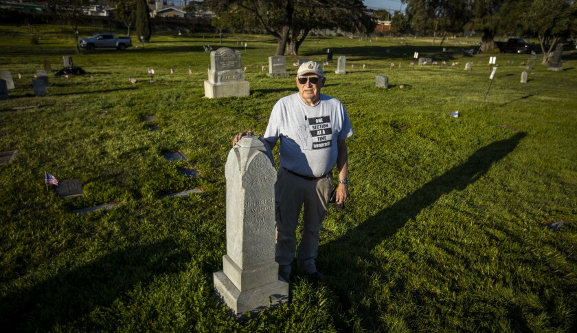 A man stands with a grave marker.