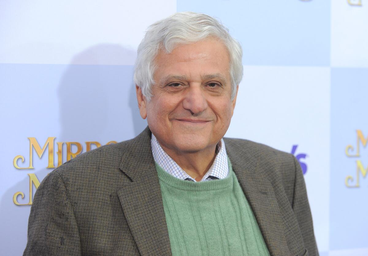 Michael Lerner smiles in a brown suit and green sweater