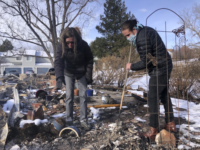 Karen England Horan with her son Robert, right, as they sift through the remains of her condo looking for jewelry and family heirlooms after it was destroyed by a wildfire that swept through her neighborhood in Louisville, Colo. on Tuesday, Jan. 4, 2022. (AP Photo/Haven Daley)