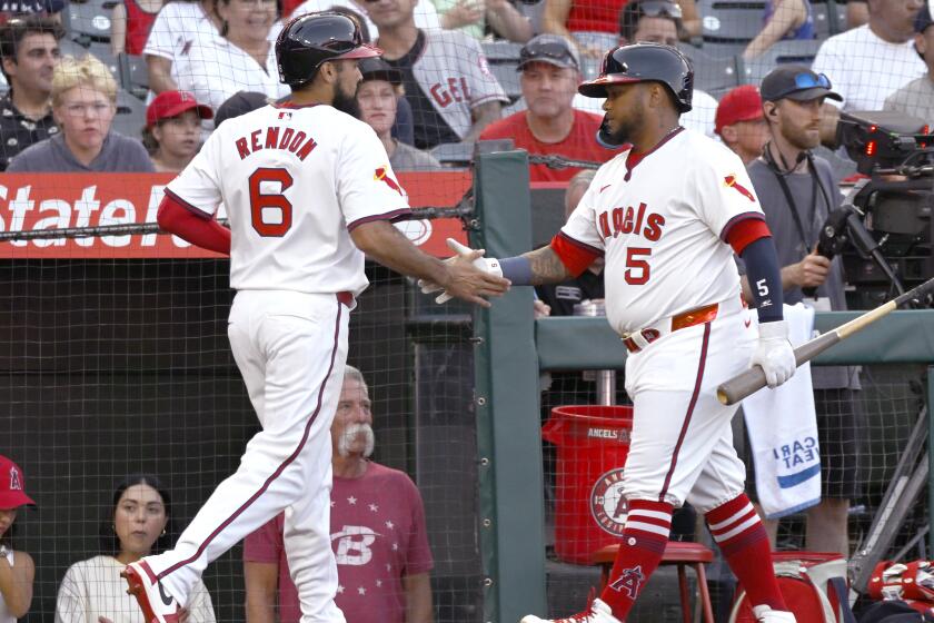The Angels' Anthony Rendon is congratulated by Willie Calhoun after being driven in on a double by Luis Rengifo