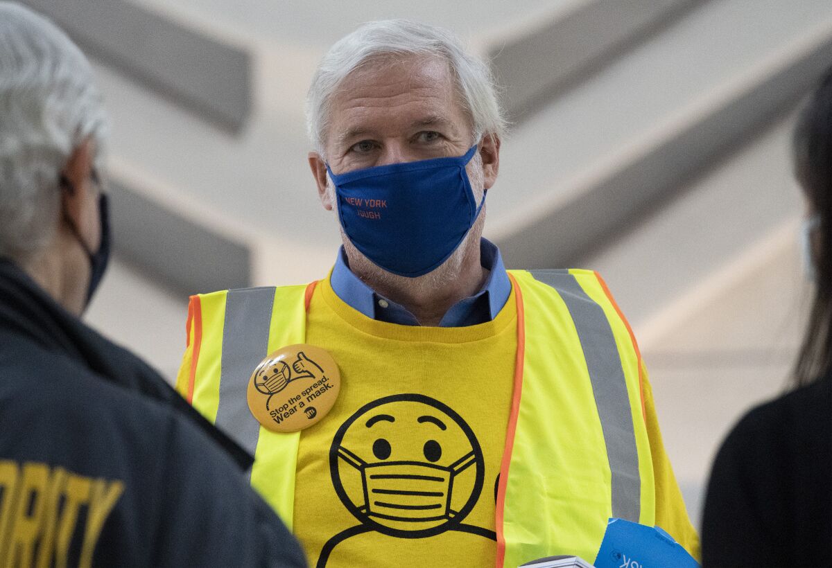 Patrick Foye wears a mask and a yellow MTA shirt and button saying Stop the spread. Wear a mask