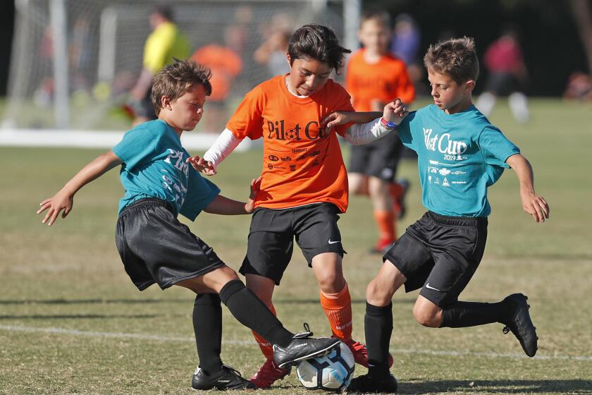 Costa Mesa Davis Elementary's Isaak Duarte, center, gets pressure from Costa Mesa Mariners Christian School defenders during a boys' third- and fourth-grade Gold Division pool-play match at the Daily Pilot Cup at Jack R. Hammett Sports Complex in Costa Mesa on Wednesday.