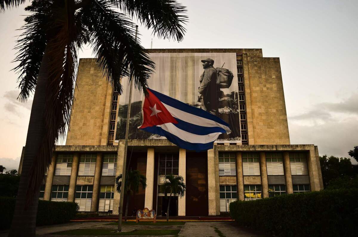 The Cuban flag hangs at half-staff in front of a picture of Fidel Castro on the facade of the Cuban national library in Havana's Revolution Square.