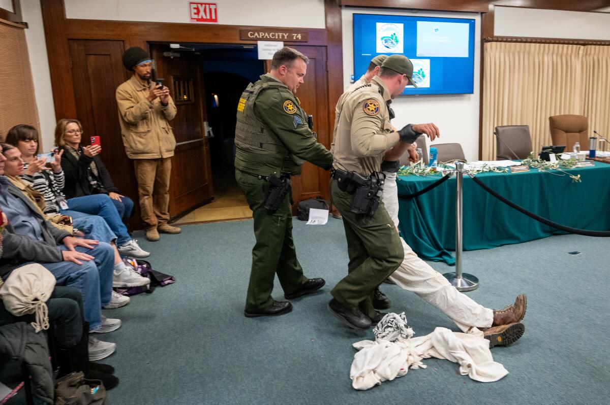 Demonstrator Cyrus Mayer is dragged from an Ojai City Council meeting on Feb. 13.