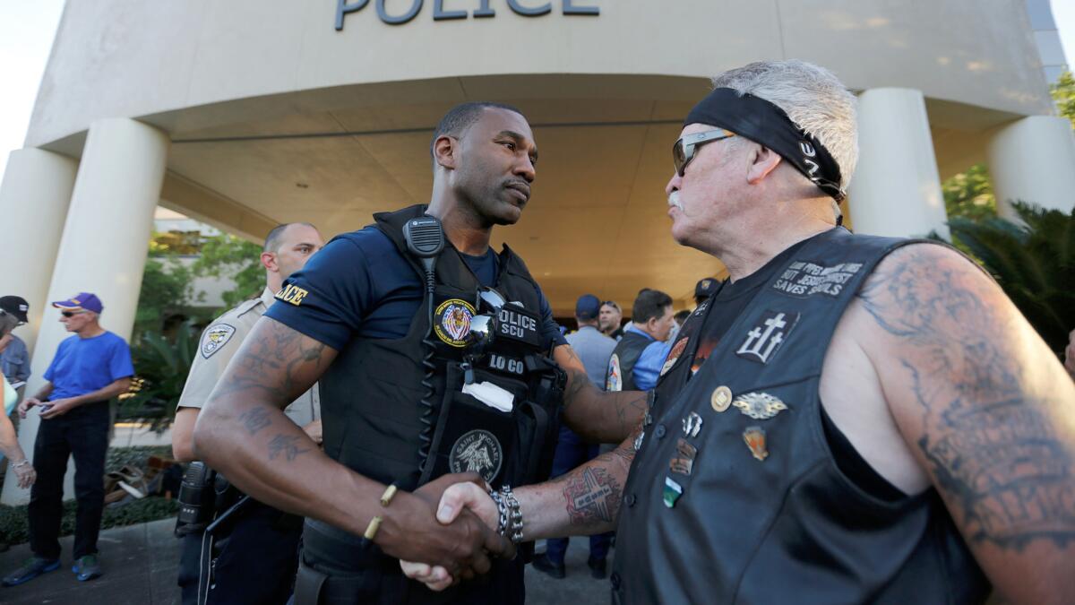 Baton Rouge Police Officer Lorenzo Coleman is greeted by Fowler Montgomery with In the Wind Ministries after a rally with nearly 400 motorcycle riders from local clubs who rode to police headquarters on Tuesday to offer support.