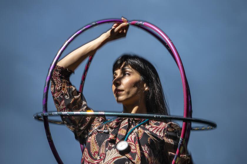 A woman wears a stethoscope around her neck and holds hula hoops