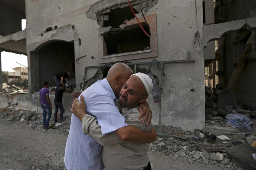 Two men embrace Sunday in front of the house of Gaza Police Chief Tayseer Batsh after it was hit by an Israeli missile.