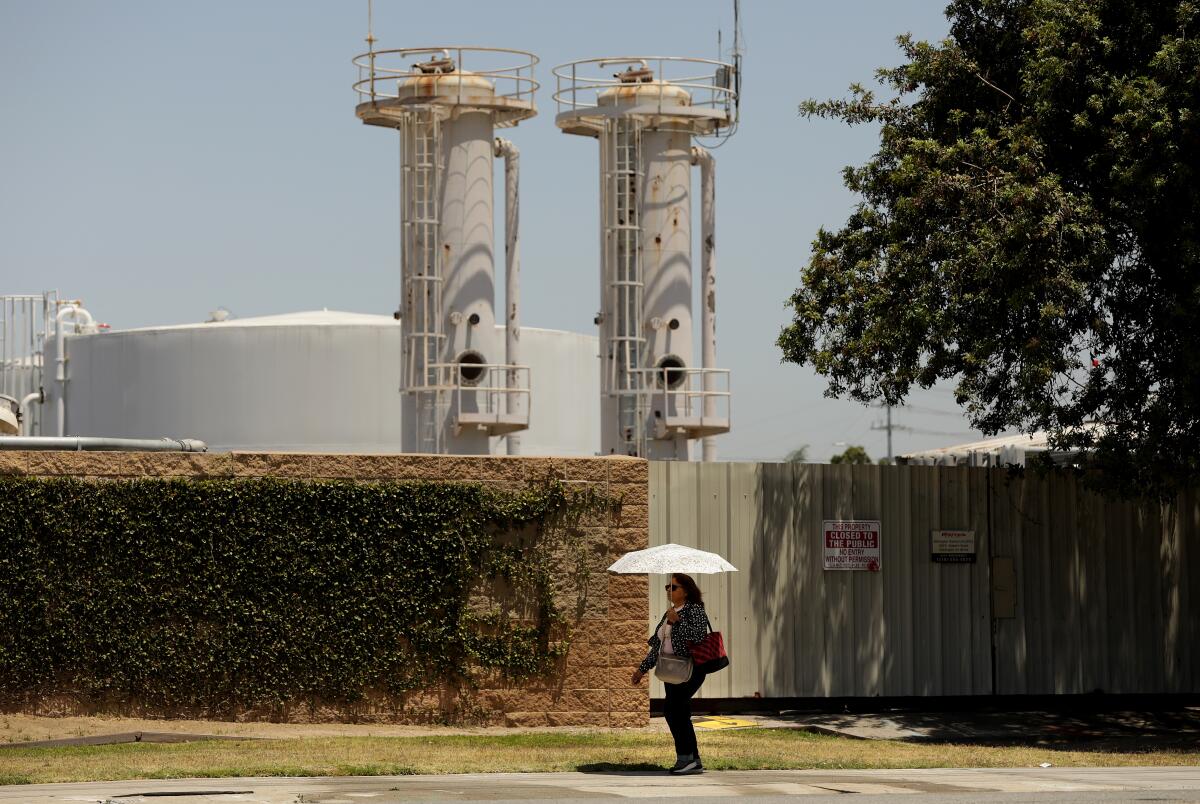 A pedestrian passes a pair of towers at an industrial site.