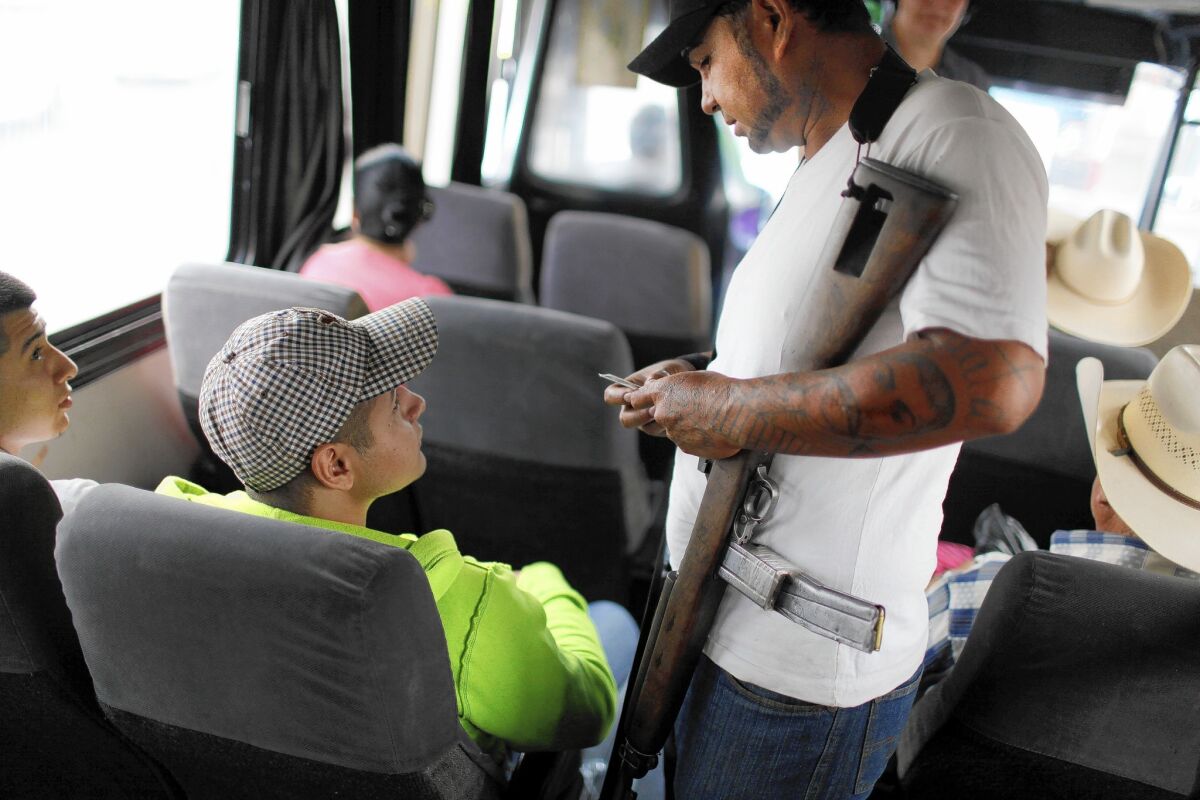 Cuauhtemoc Espejo checks a passenger's ID on a bus near Apatzingan in the Mexican state of Michoacan, where vigilante bands have taken over large areas that had been dominated for nearly a decade by drug and extortion cartels.
