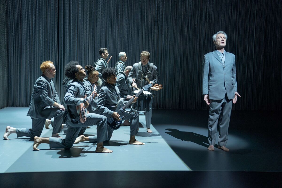 A scene from "American Utopia" shows musicians clad in grey suits in formation behind David Byrne