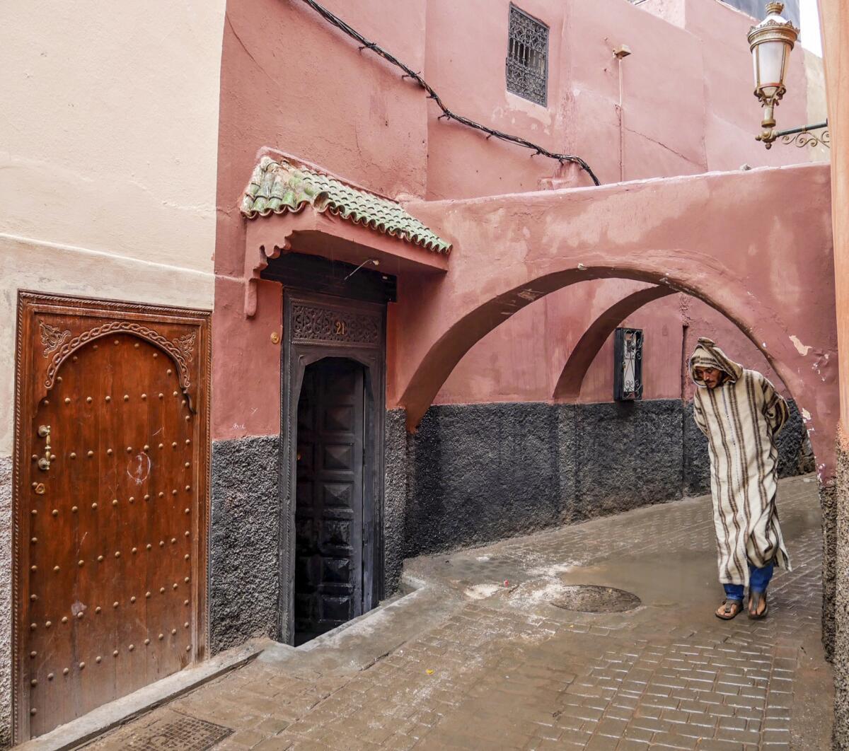 A man in a djellaba, a long, loose-fitting robe, ducks under one of the many archways in the ancient walled city in Fez.