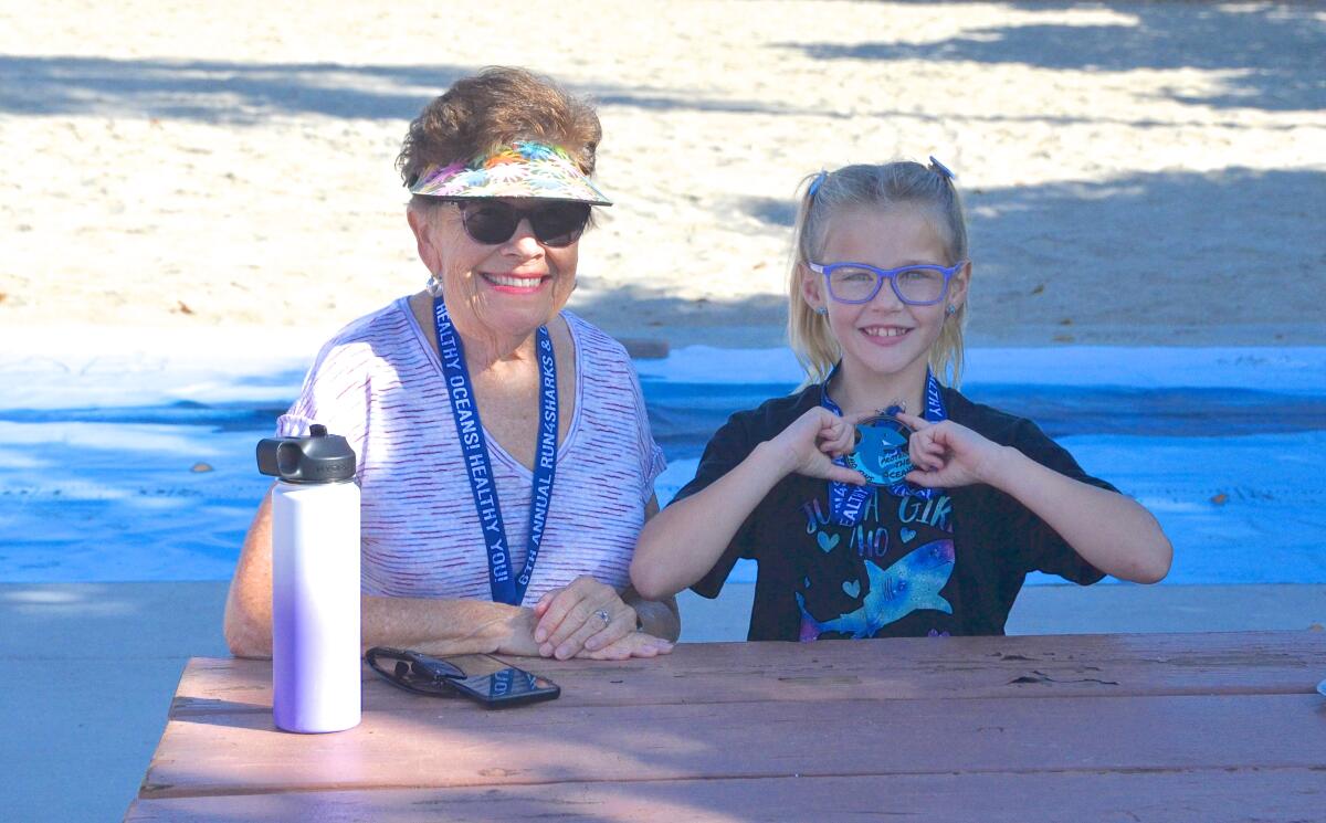 Penny Boyer displays her medal beside her grandmother, Ruth Seamark, at the Run 4 Sharks event.
