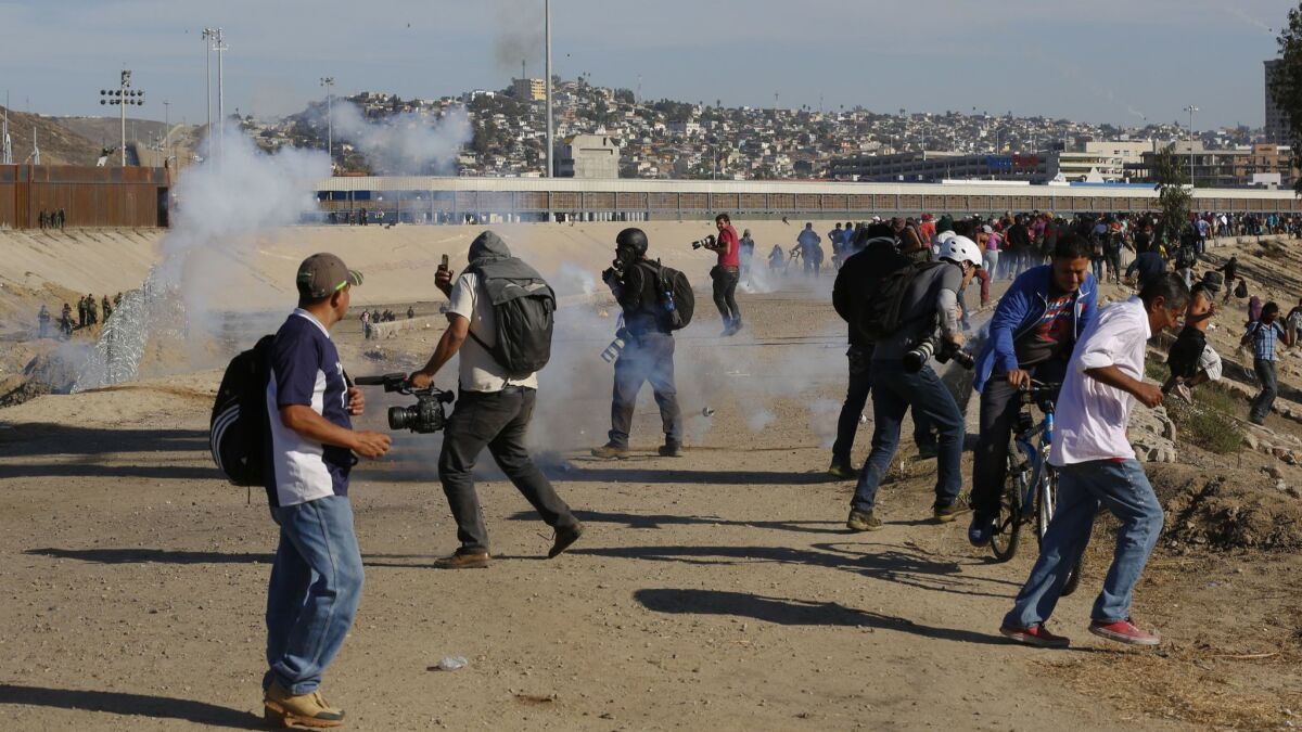 In this Nov. 25, 2018 file photo, a migrant runs from tear gas launched by U.S. agents, amid members of the press covering the Mexico-U.S. border, after a group of migrants got past Mexican police at the Chaparral crossing in Tijuana, Mexico.