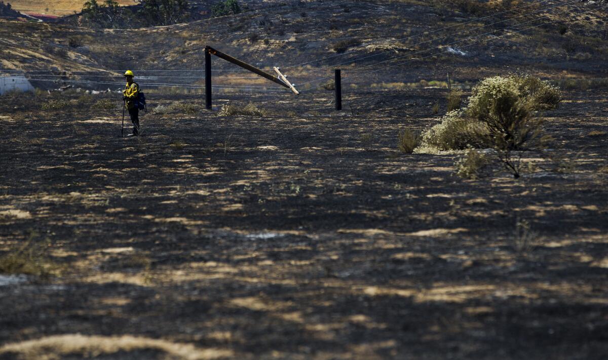 A firefighter checks on hot spots after the Manzanita fire burned 5,800 acres of rugged terrain and knocked down power poles off Highland Springs Avenue on June 27, 2017 south of Beaumont. (Gina Ferazzi / Los Angeles Times)