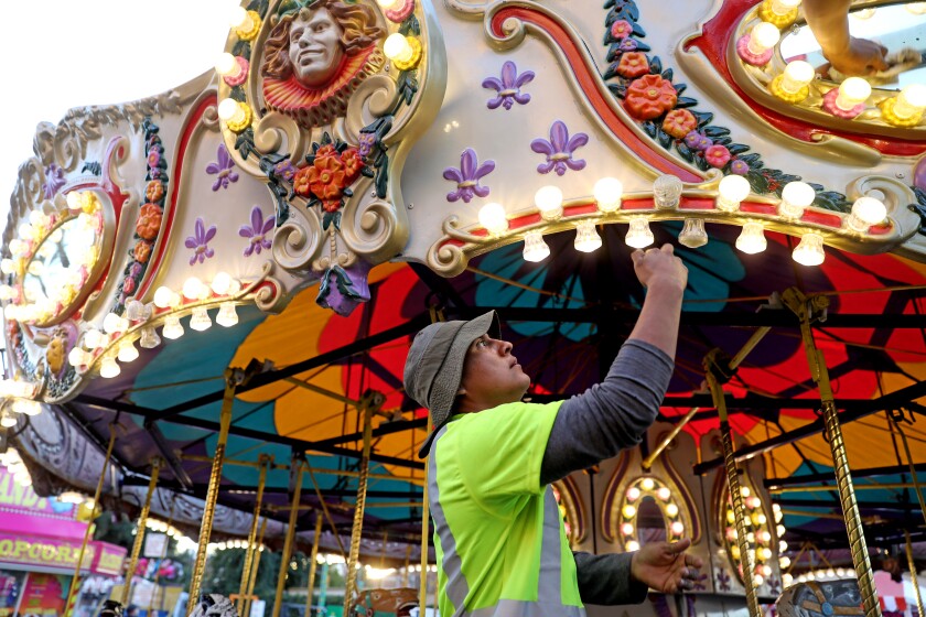 A worker replaces lightbulbs on a merry-go-round