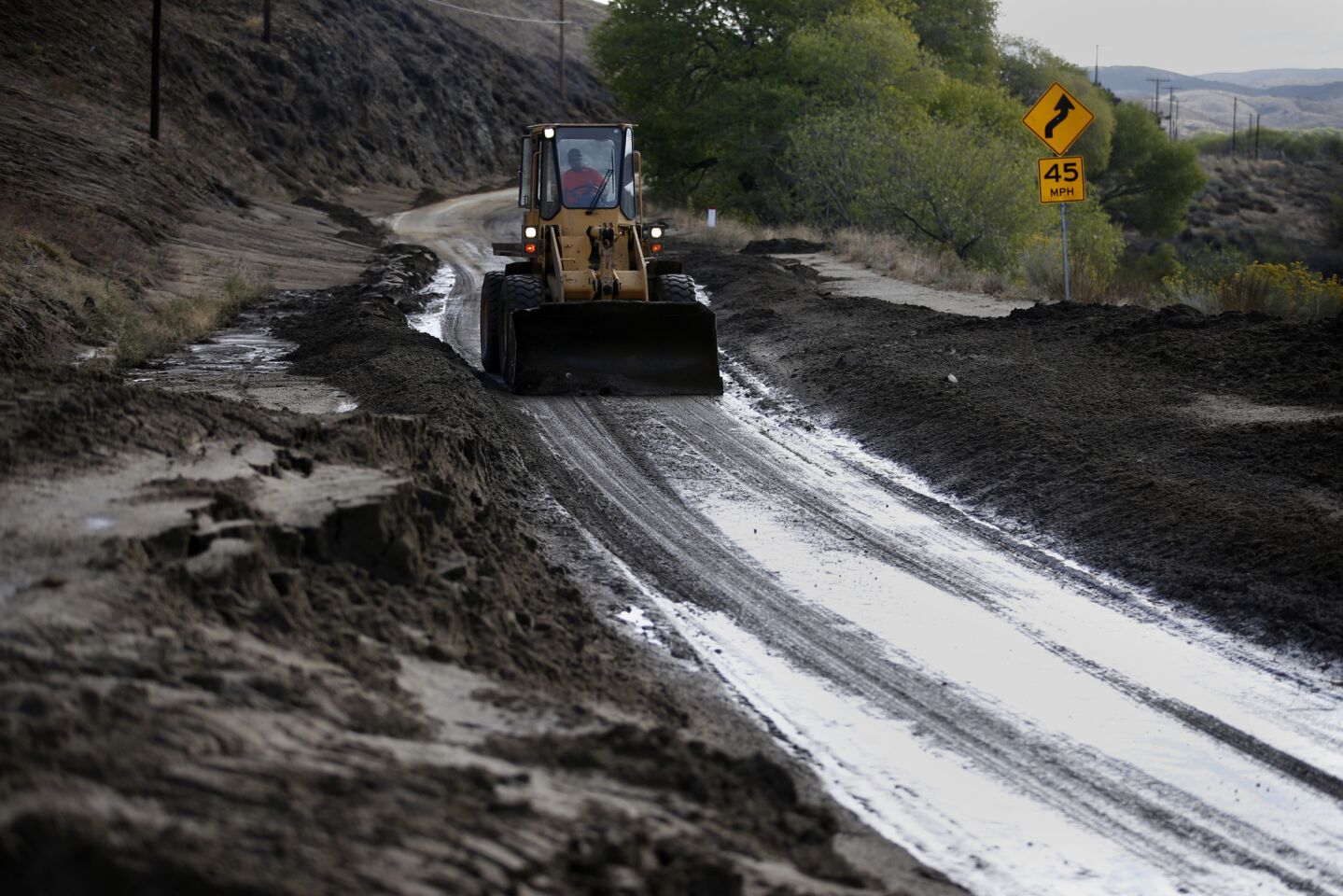 A bulldozer clears mud from Lake Elizabeth Road after several cars were inundated after a deluge Thursday.