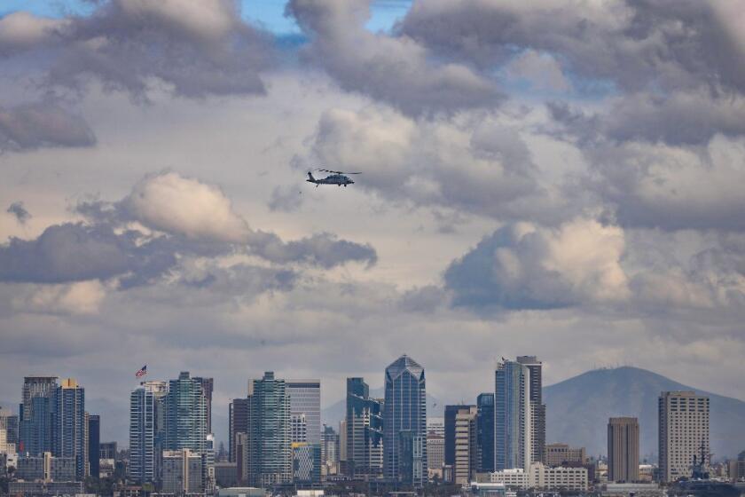 With the San Diego downtown skyline as backdrop, a Navy helicopter prepares to land at Naval Air Station North Island.