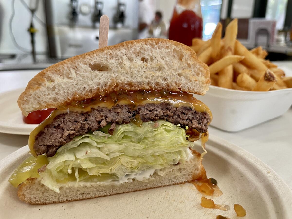 A steakburger cut in half, with an order of french fries