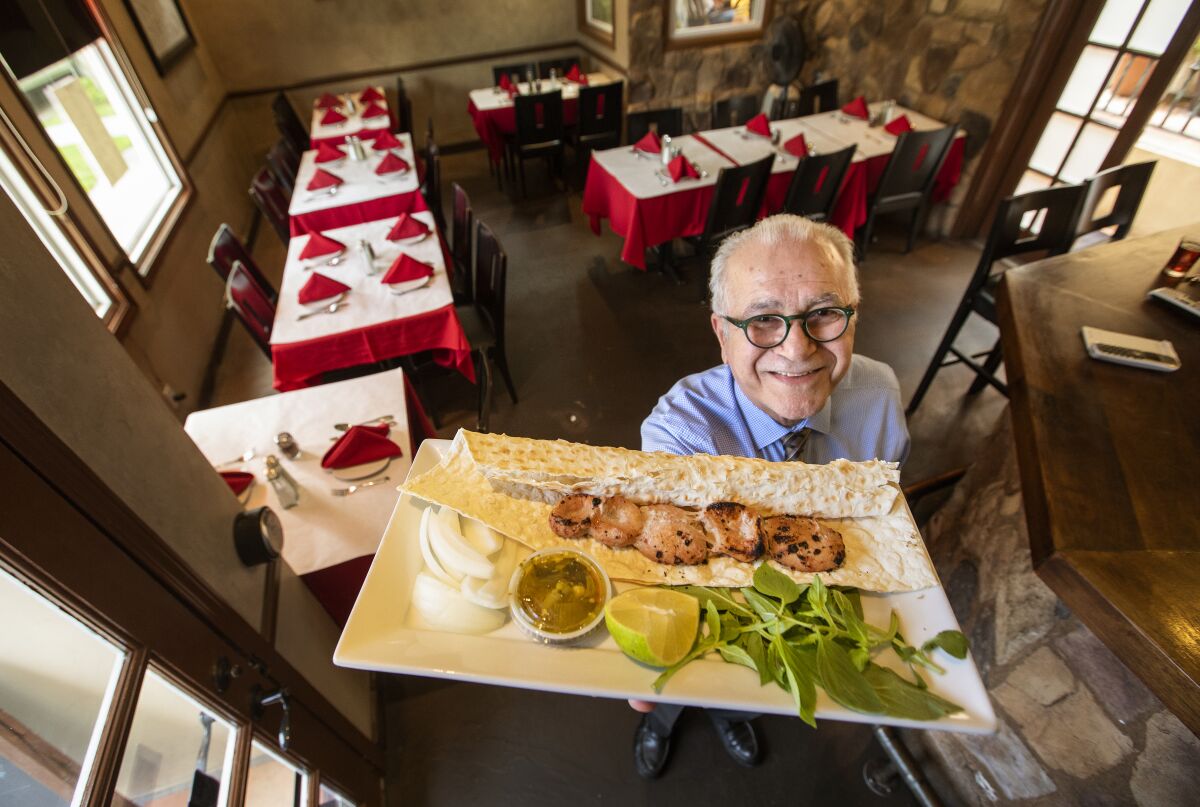 Farhad Pourbastani, manager at Attari Grill, holds up a plate featuring donbalan, grilled lamb testicle. "It's amazing to be eating this dish in L.A.," said Anissa Helou.