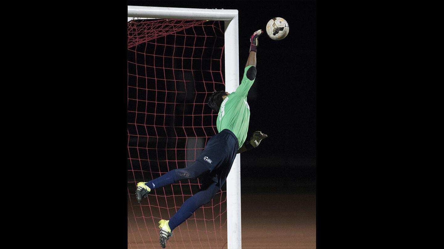 Newport Harbor's Emilio Carbajal makes a leaping save on a shot on goal by Los Alamitos's Ryan Mendoza (not pictured) during a Sunset League game on Friday, January 19.