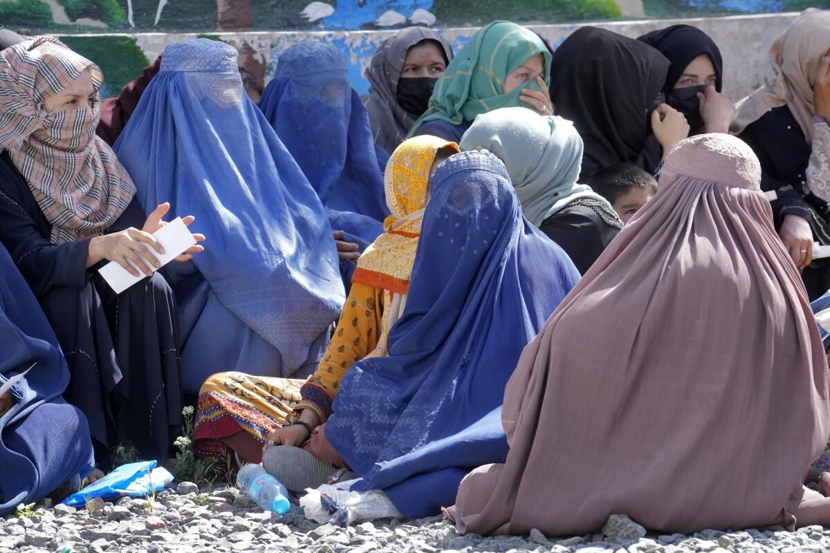 Afghan women wait to receive food rations distributed by a Saudi humanitarian aid group, in Kabul, Afghanistan, Monday, April 25, 2022. Afghanistan’s Taliban rulers on Saturday, May 7, ordered all Afghan women to wear head-to-toe clothing in public, a sharp hard-line pivot that confirmed the worst fears of rights activists and was bound to further complicate Taliban dealings with an already distrustful international community. (AP Photo/Ebrahim Noroozi)