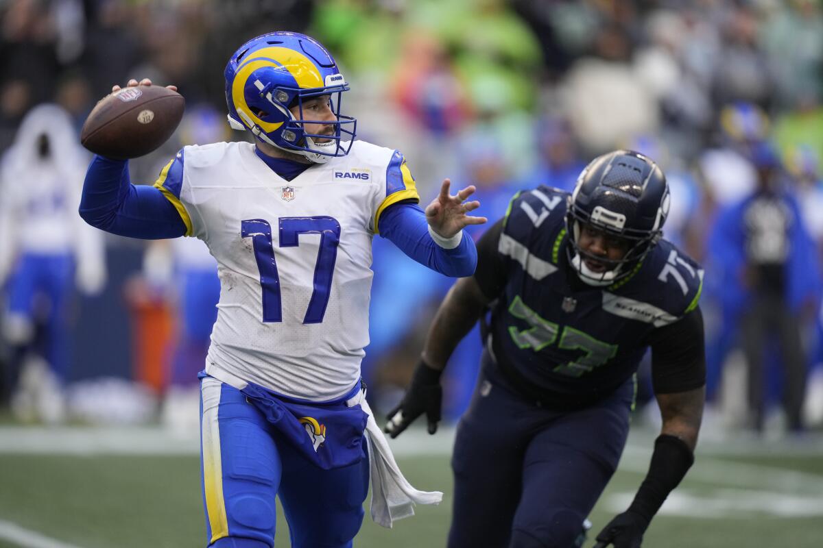 Rams quarterback Baker Mayfield throws as Seattle Seahawks defensive tackle Quinton Jefferson chases him.