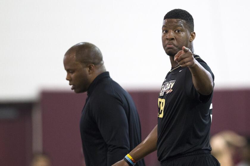 Jameis Winston, right, gestures as he walks beside trainer George Whitfield during Florida State's pro day Tuesday in Tallahassee, Fla.