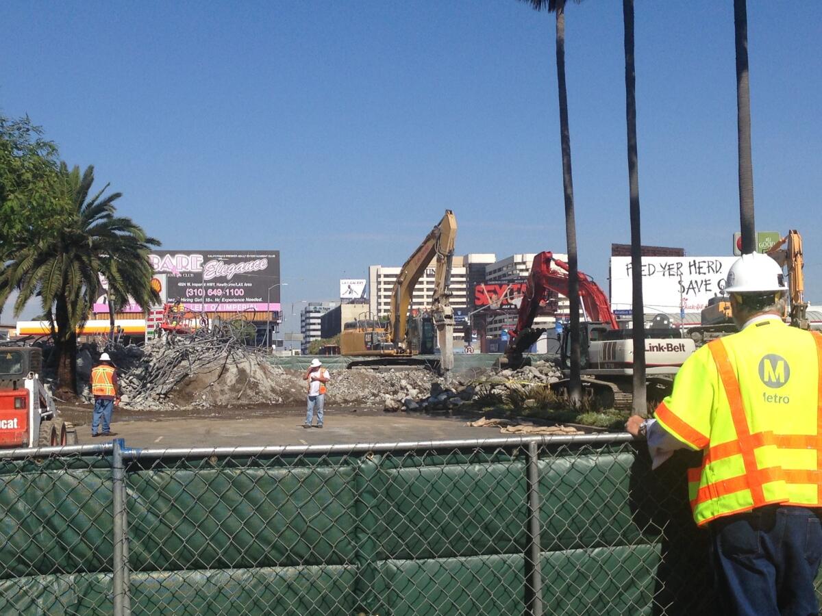 Demolition crews work Saturday at knocking down a railroad bridge on Century Boulevard near the entrance to Los Angeles International Airport.