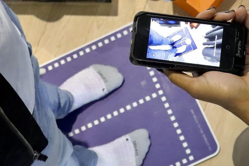 Nike officials demonstrate the company's foot-scanning tool on its app that will measure and remember the length, width and other dimensions of customers' feet after they point a smartphone camera to their toes, Wednesday April 24, 2019, in New York. (AP Photo/Bebeto Matthews)