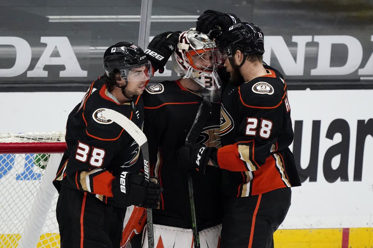 Ducks goaltender John Gibson, center, is congratulated by Derek Grant (38) and Jani Hakanpaa (28)