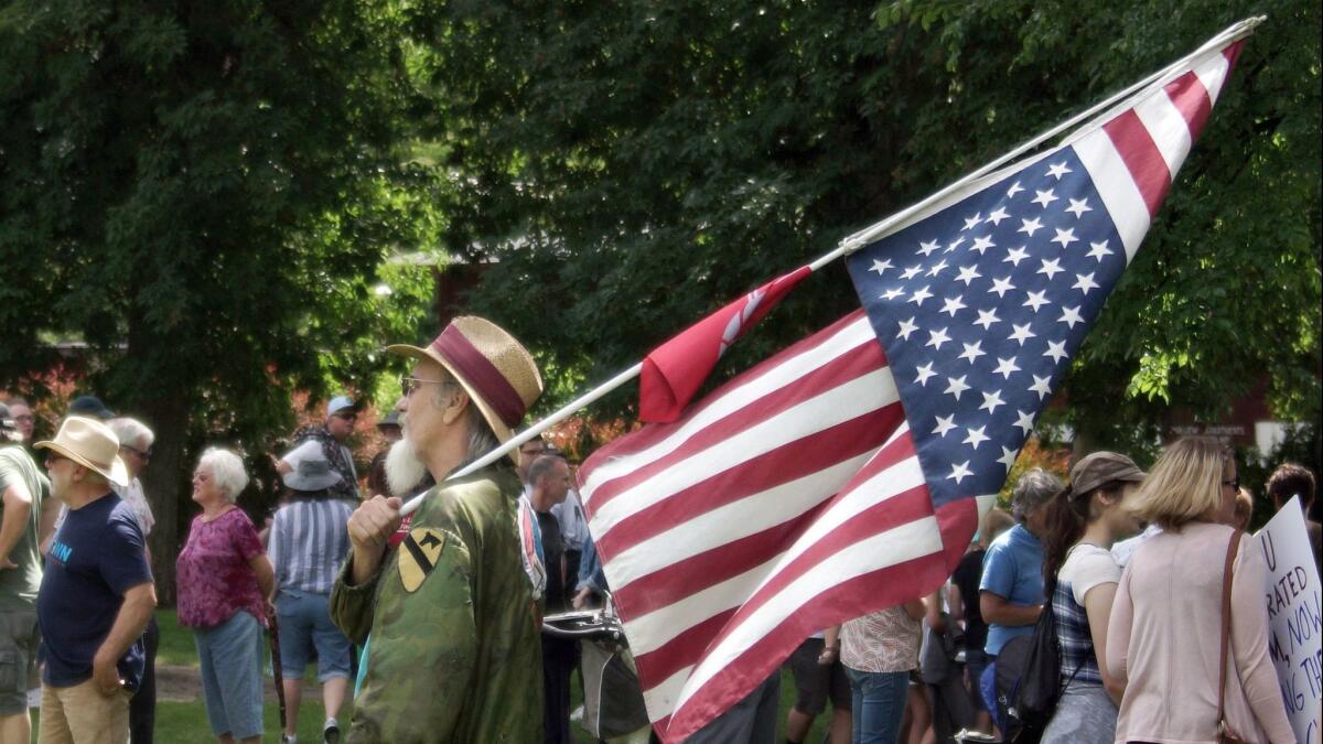 Vietnam War veteran and peace activist David Armstrong carries an American flag in the distress position during a Families Belong Together march and rally on Saturday in Pullman, Wash.