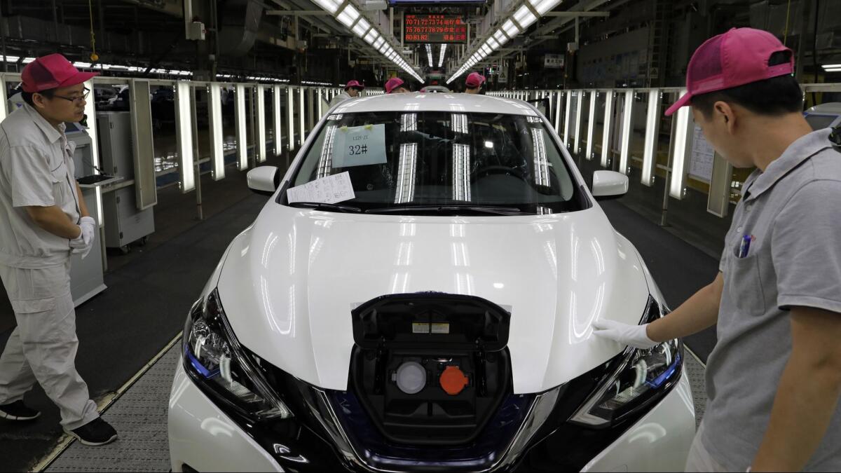 Chinese workers inspect a Nissan Sylphy Zero Emission, Nissan's first all-electric vehicle built in China, at a production line in Guangzhou, in Guangdong province.