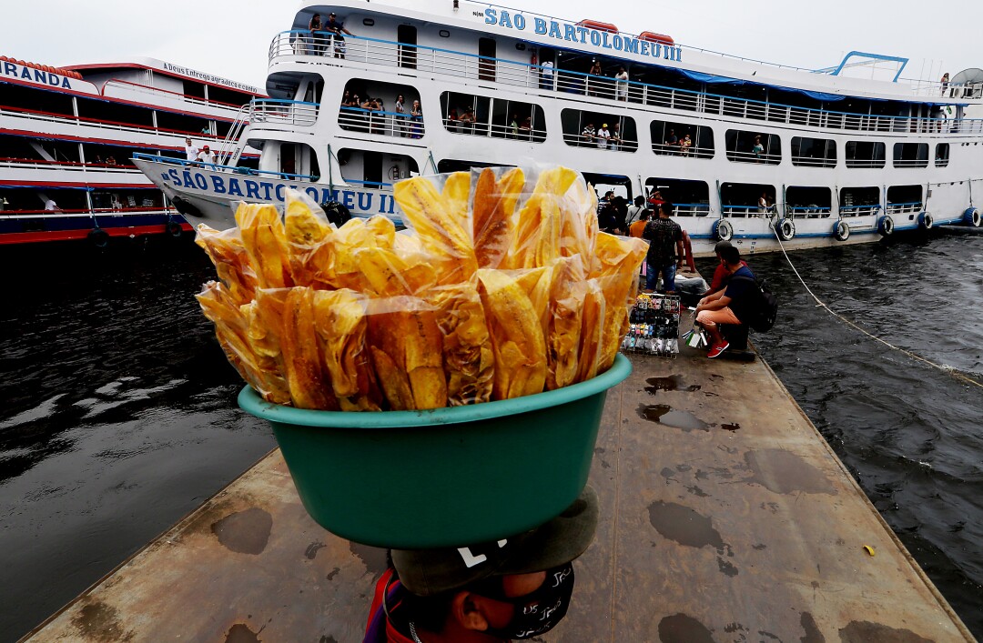 Vendors carrying items in buckets toward a boat 