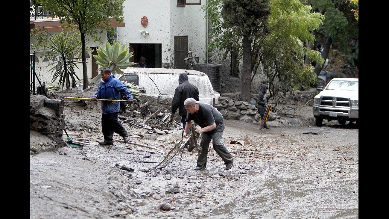 Local residents remove debris and mud from in front of their home on Country Club Drive in Burbank on Tuesday, Jan. 9, 2018. Two vehicles were destroyed in the quick-moving mud flow.