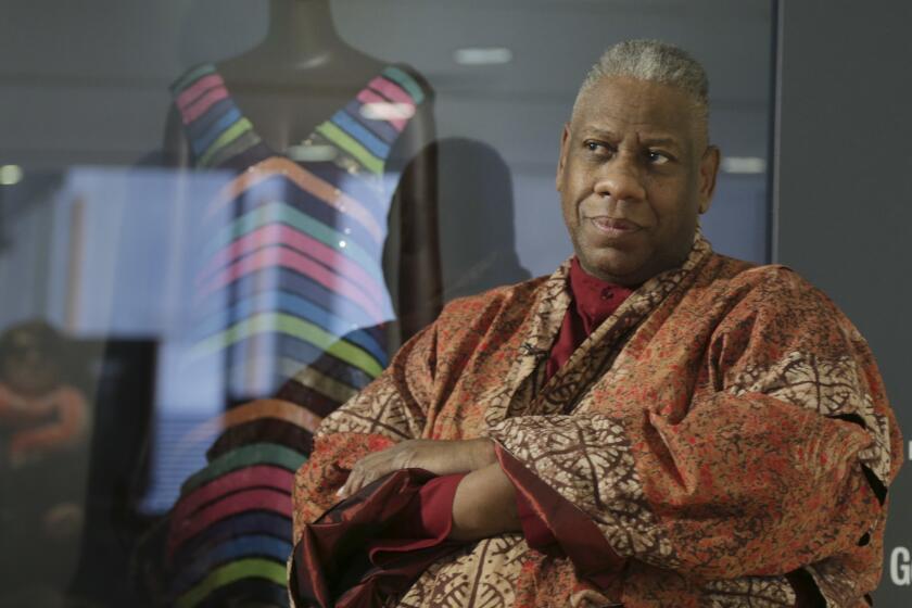 André Leon Talley posing with his arms crossed in an orange robe