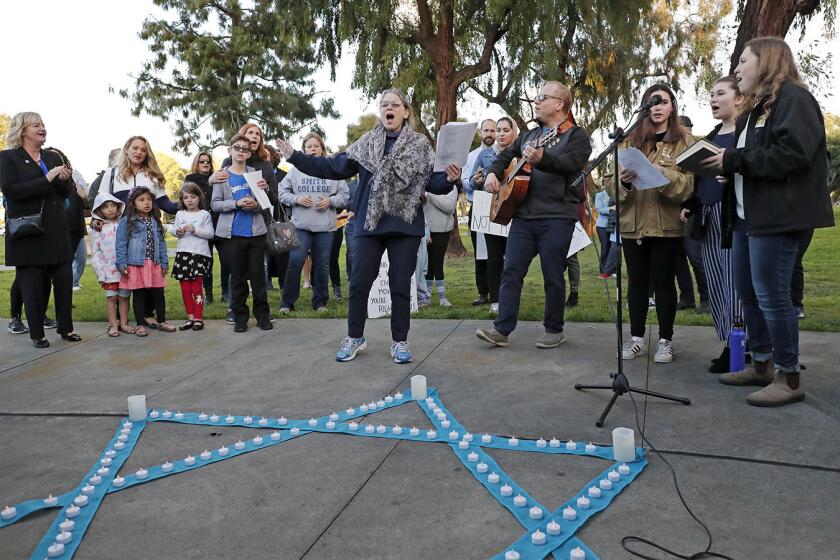 Jewish Collaborative of Orange County founder Rabbi Marcia Tilchin, center, leads a group in song during a shabbat service and vigil as part of a solidarity rally at TeWinkle Park in Costa Mesa on Friday to address anti-semitism in the community and express solidarity. The vigil was in response to community outrage over photos from a weekend party that featured area high school students giving Nazi salutes over a swastika fashioned from cups during a drinking game.