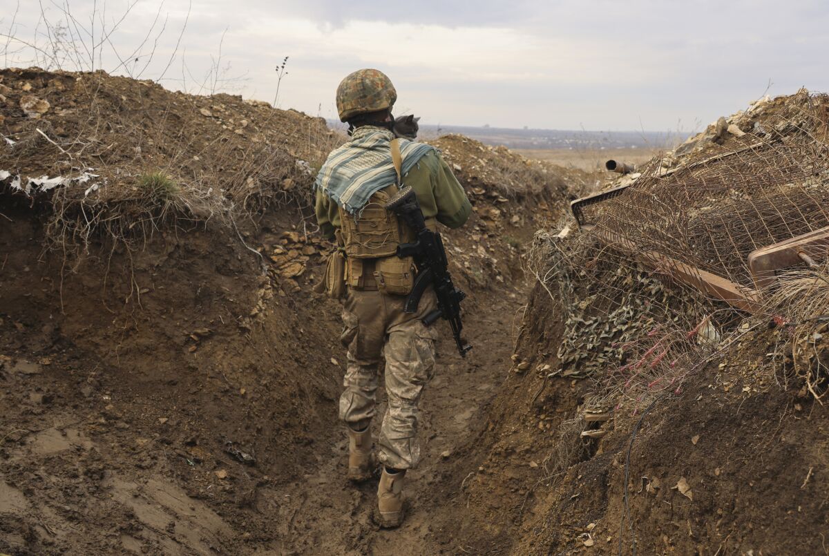 A Ukrainian soldier holds a cat and walks in a trench on the line of separation from pro-Russian rebels near Debaltsevo, Donetsk region, Ukraine, Ukraine Friday, Dec 3, 2021. In this Friday, the Ukrainian defense minister warned that Russia could invade his country next month. Russia-West tensions escalated recently with Ukraine and its Western backers becoming increasingly concerned that a Russian troop buildup near the Ukrainian border could signal Moscow's intention to invade. (AP Photo/Andriy Dubchak)
