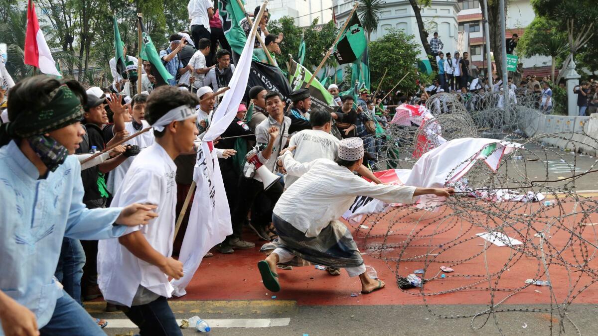 Muslim protesters are confronted by razor wire blocking a road leading to the presidential palace during a rally against Jakarta Gov. Basuki Tjahaja Purnama on Friday.