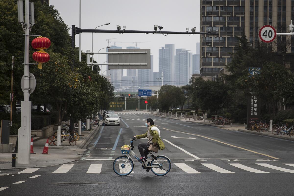 A woman bicycles through the deserted streets of Wuhan, China, on Tuesday.